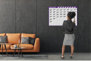 Woman dressed smartly, contemplates the Badass Beat Boards scene board in a living room setting